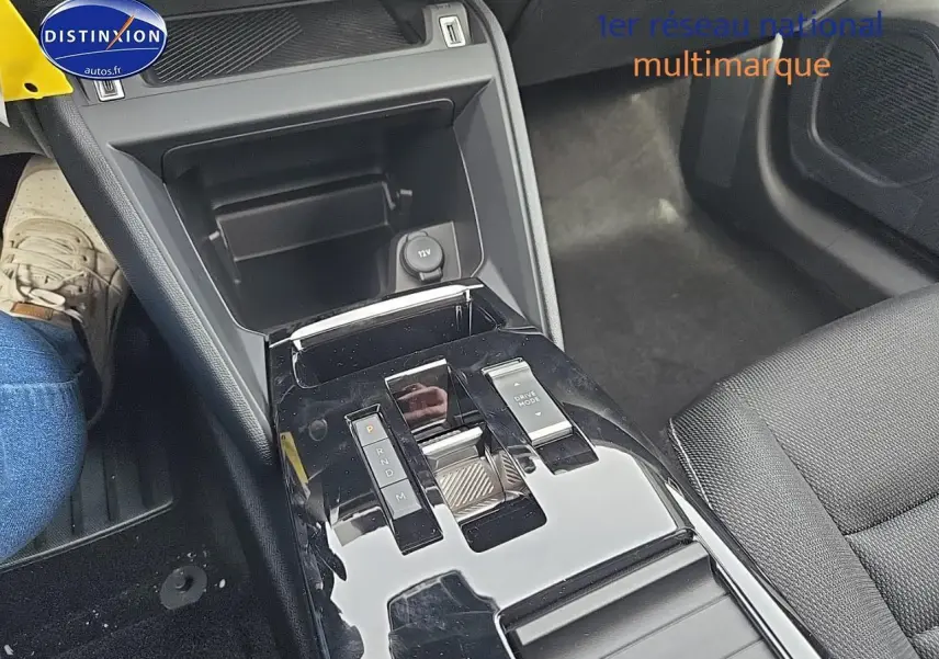 Vue rapprochée de la console centrale noire brillante avec sélecteur de boîte automatique et accoudoir tissu noir dans une Citroën C4 blanche.