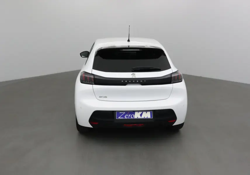 Vue arrière d'une Peugeot 208 blanche 2024 avec vitres teintées et logo Peugeot bien visible.