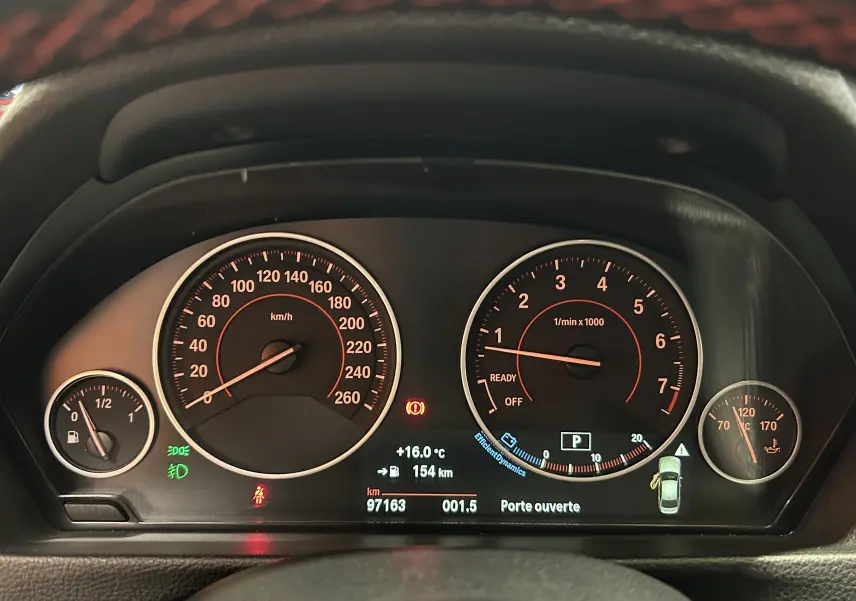 Tableau de bord de BMW Série 3 320i blanc 2018, affichant vitesse, compte-tours et alertes au centre.