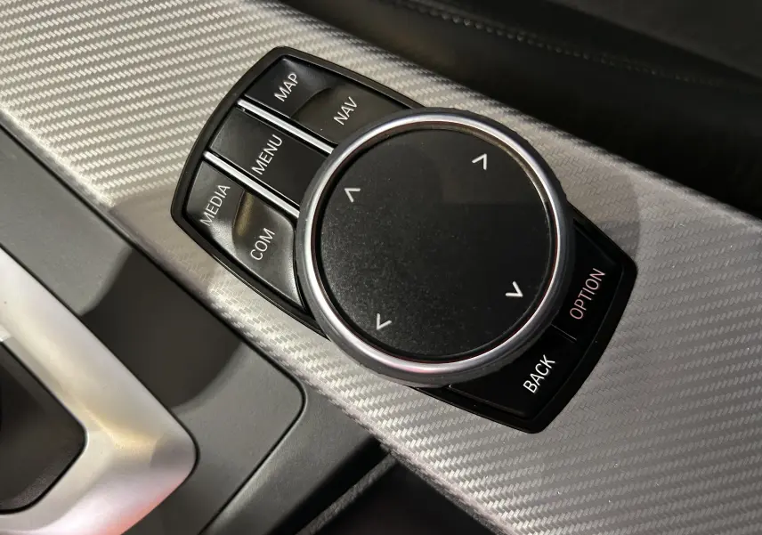 Gros plan sur la molette de commande du système GPS dans l'habitacle d'une BMW Série 3 blanche de 2018.