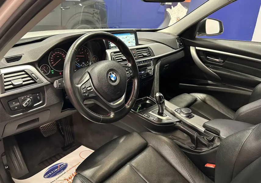 Intérieur noir de BMW Série 3 320i 2018 vu côté conducteur, avec tableau de bord et écran GPS lumineux.