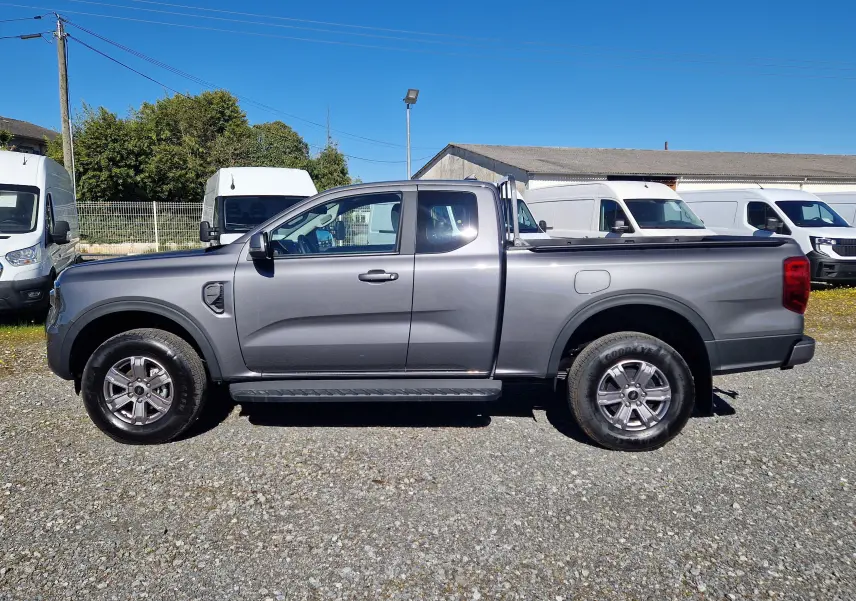 Vue de profil côté gauche d'un Ford Ranger Super Cabine gris carbone 2026 avec benne et jantes alliage.