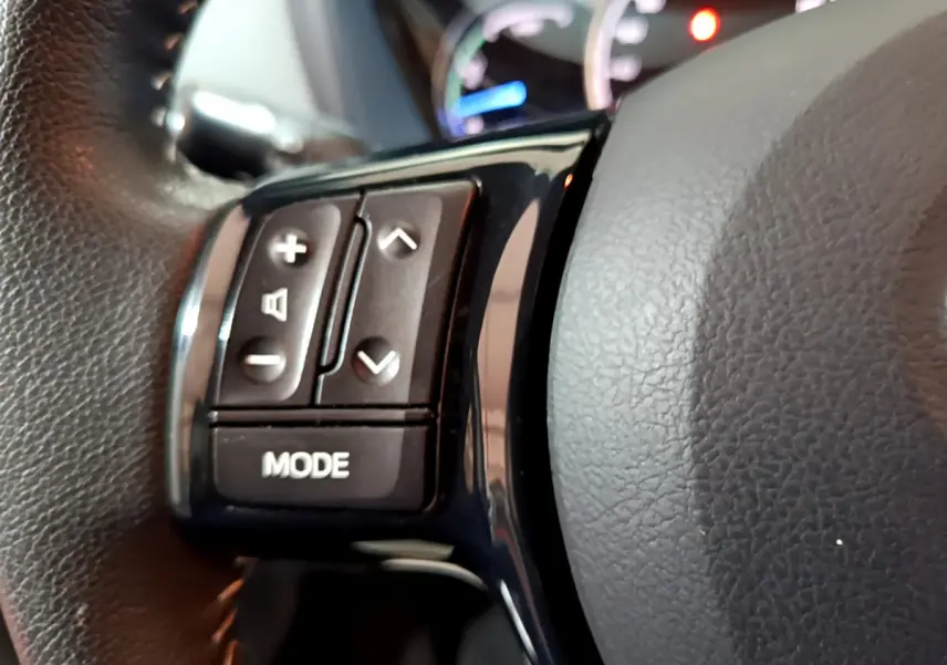 Gros plan sur les commandes du volant noir de la Toyota Yaris 1.5 Hybride 2020, avec boutons de volume et mode.