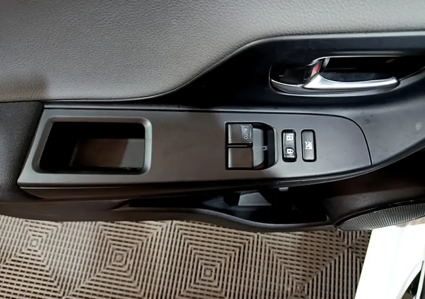 Gros plan sur la commande de lève-vitre côté conducteur de la Toyota Yaris blanche 2020, avec poignée intérieure chromée.