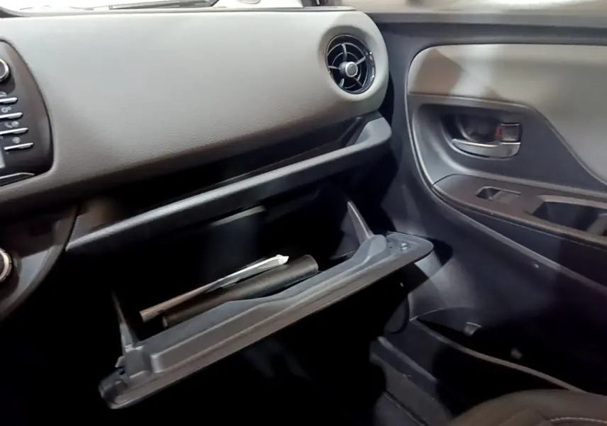 Vue intérieure côté passager de la Toyota Yaris blanche 2020, boîte à gants ouverte avec documents visibles.
