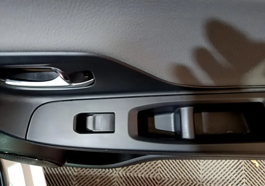 Gros plan sur la poignée intérieure et les commandes de fenêtre côté conducteur d'une Toyota Yaris blanche 2020.