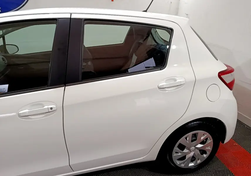 Vue latérale droite d'une Toyota Yaris blanche 2020, mettant en valeur la porte arrière et la roue arrière.