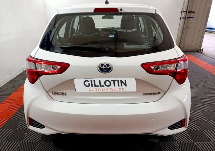 Vue arrière d'une Toyota Yaris blanche hybride 2020 avec feux arrière nets et logo Toyota visible.