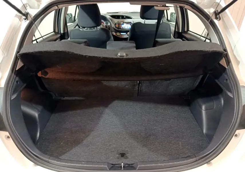 Coffre ouvert vu de l'arrière d'une Toyota Yaris blanche, montrant l'espace de chargement et l'intérieur des sièges avant.