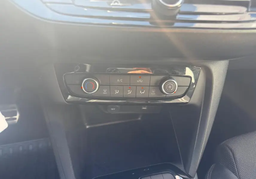 Gros plan sur la console centrale de l’Opel Corsa rouge 2025, mettant en valeur les commandes de climatisation manuelle.