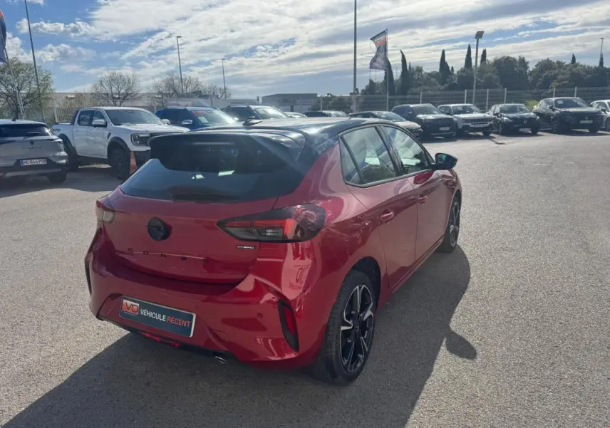 Vue 3/4 arrière droite d'une Opel Corsa rouge 2025 avec jantes alliage noires et feux arrière LED distinctifs.