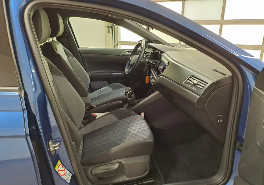 Vue intérieure côté conducteur de la Volkswagen Polo Bleu Récif 2025, avec sièges tissu et tableau de bord moderne.
