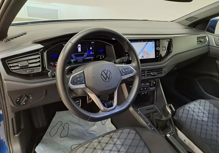 Vue intérieure du poste de conduite de la Volkswagen Polo 2025, volant multifonction et écran tactile avec navigation visible.