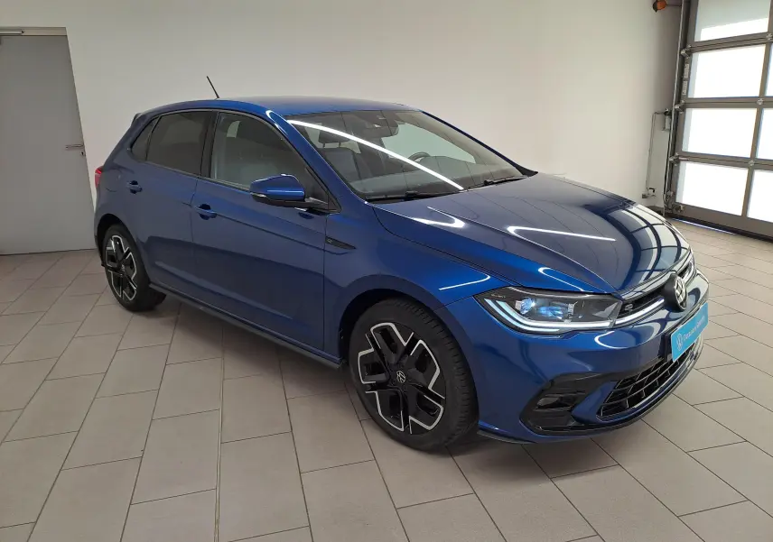 Volkswagen Polo 1.0 TSI R-Line Bleu Récif vue 3/4 avant droit en intérieur avec jantes noires distinctives.