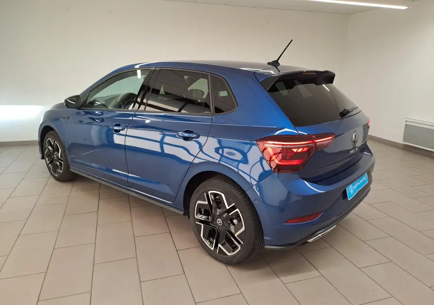 Vue 3/4 arrière droite d'une Volkswagen Polo 2025 Bleu Récif métallisé avec jantes R-Line distinctives en intérieur neutre.