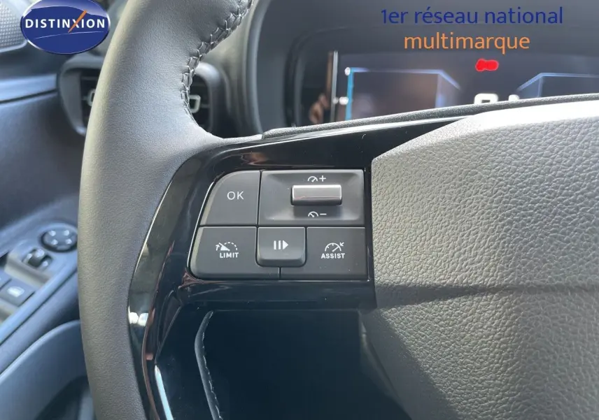 Gros plan sur les commandes à gauche du volant noir du Citroën Berlingo 2026, avec tableau de bord numérique en arrière-plan.
