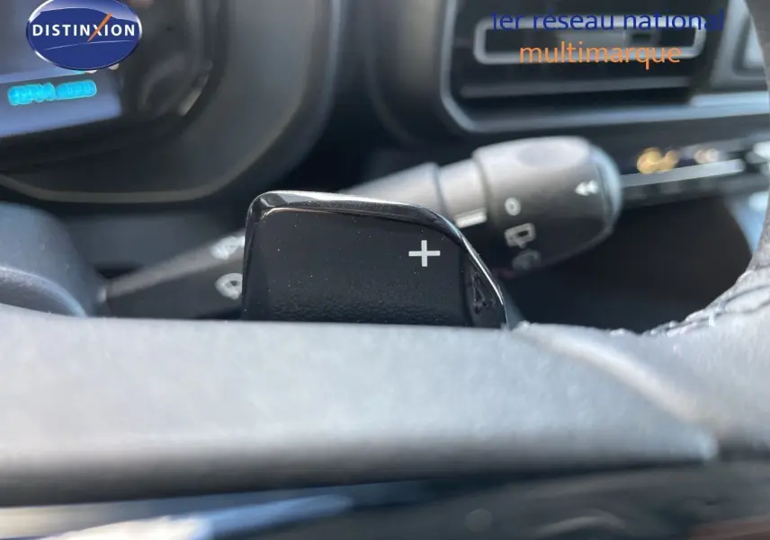 Gros plan sur la palette de passage de vitesses "+" côté droit du volant dans l'habitacle d'un Citroën Berlingo noir.