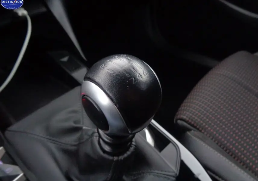 Gros plan sur le levier de vitesse manuel noir du DS3 Crossback blanc banquise, avec siège avant à motifs visibles.