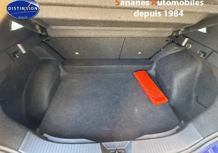 Coffre ouvert d'un Nissan Qashqai 1.5 e-Power bleu foncé, montrant un espace de rangement vide avec un objet rouge.