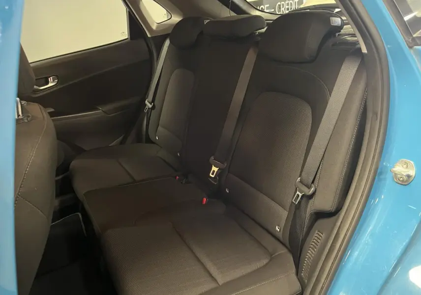 Vue intérieure côté droit sur les sièges arrière noirs du Hyundai Kona bleu 2022 avec porte ouverte.