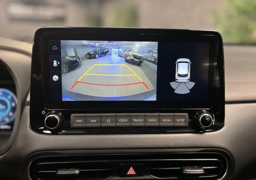 Écran tactile central affichant la caméra de recul et l’aide au stationnement du Hyundai Kona bleu 3/4 arrière.