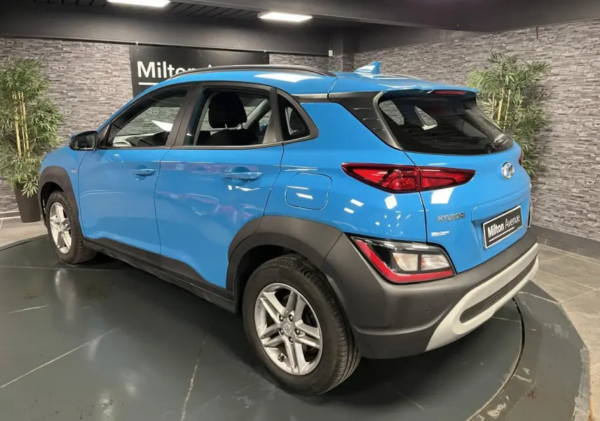 Vue 3/4 arrière droite d'un Hyundai Kona bleu avec protections noires et antenne aileron de requin.