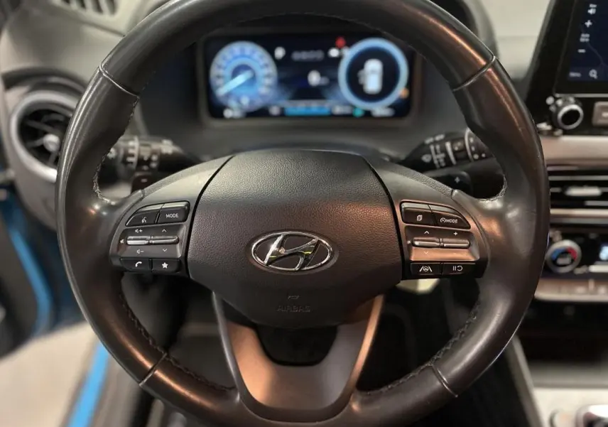 Volant cuir noir du Hyundai Kona 2022 avec commandes intégrées et tableau de bord numérique en arrière-plan.