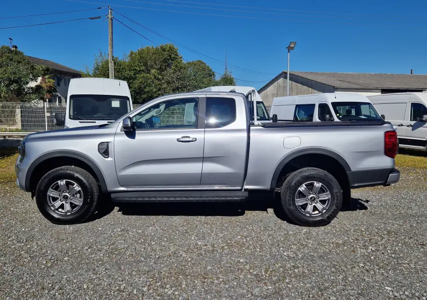 Vue de profil côté gauche d'un Ford Ranger Super Cabine gris iconic avec roues alliage et barre de protection arrière.