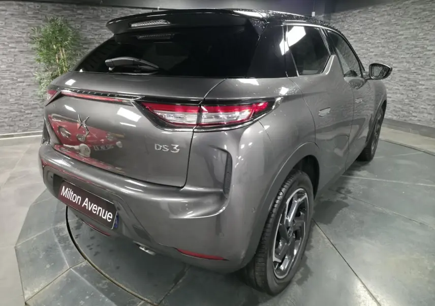 Vue 3/4 arrière droite d'un DS3 Crossback gris métallisé avec toit noir et jantes alliage 18 pouces.