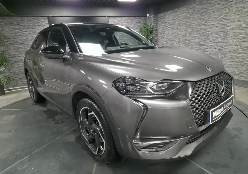 Vue 3/4 avant droite d’un DS3 Crossback gris métallisé avec calandre DS Wings chromée dans un showroom.