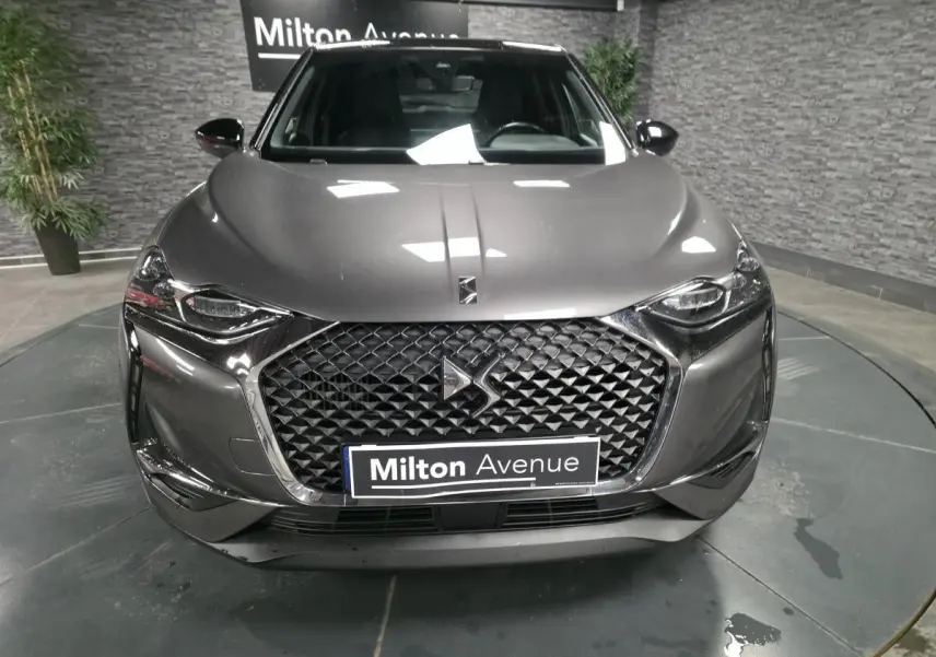 Vue frontale d'un DS3 Crossback gris métallisé avec calandre DS Wings chromée et phares LED, en showroom.