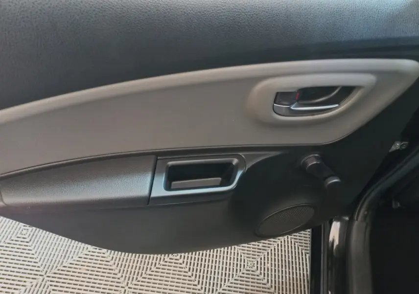 Intérieur côté droit de la porte arrière noire de la Toyota Yaris 2018 avec poignée et commande de vitre manuelle.