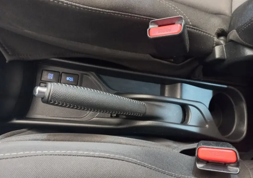 Vue rapprochée de la console centrale noire de la Toyota Yaris 2018, avec frein à main et boutons Eco Mode et traction.