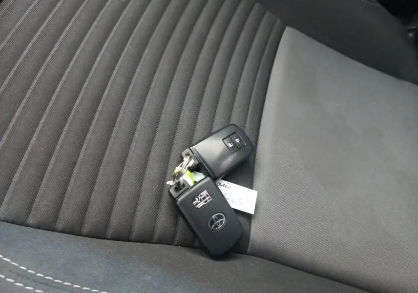 Clé Toyota posée sur la sellerie noire en tissu du siège avant de la Yaris 1.5 VVT-I Hybrid France Business.