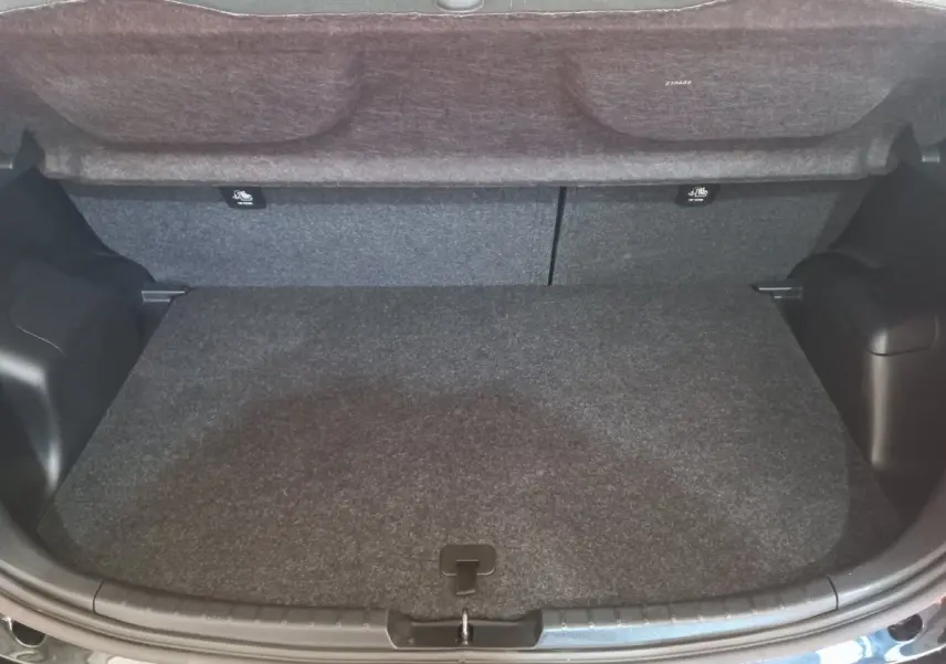 Coffre ouvert vu de l'arrière d'une Toyota Yaris noire, montrant l'espace de chargement et la tablette de séparation.