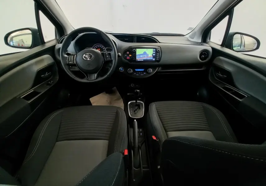 Vue intérieure avant de la Toyota Yaris noire 2018, tableau de bord avec écran tactile et volant multifonctions cuir.