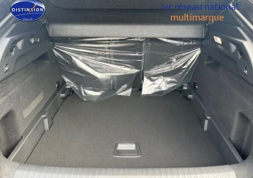 Vue intérieure du coffre spacieux du Peugeot 3008 gris titane, avec banquette arrière protégée par film plastique.