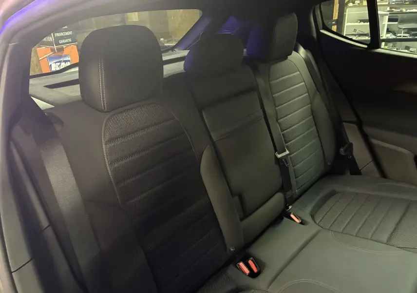 Vue intérieure des sièges arrière noirs en cuir de l'Alfa Romeo Tonale 1.3 PHEV 280 BVA TI, avec ceinture de sécurité visible.