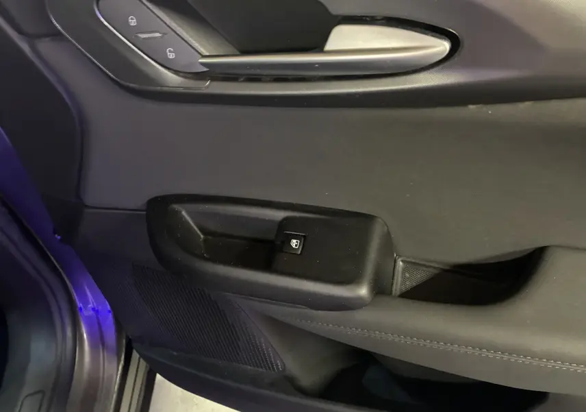 Détail de la porte intérieure côté conducteur de l'Alfa Romeo Tonale 1.3 PHEV gris foncé avec commande de verrouillage et poignée argentée.