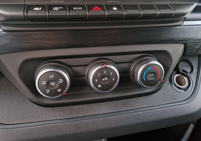 Gros plan sur les commandes de climatisation et boutons de fonction du tableau de bord du Nissan Primastar blanc, version 2025.