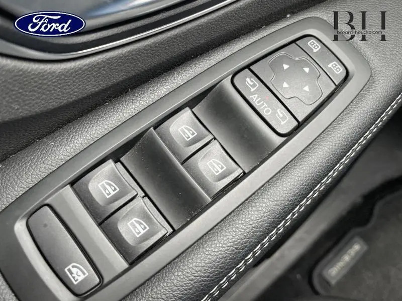 Gros plan sur les commandes de lève-vitres et réglages des rétroviseurs sur la porte côté conducteur d'un Renault Scénic blanc nacré 2022.