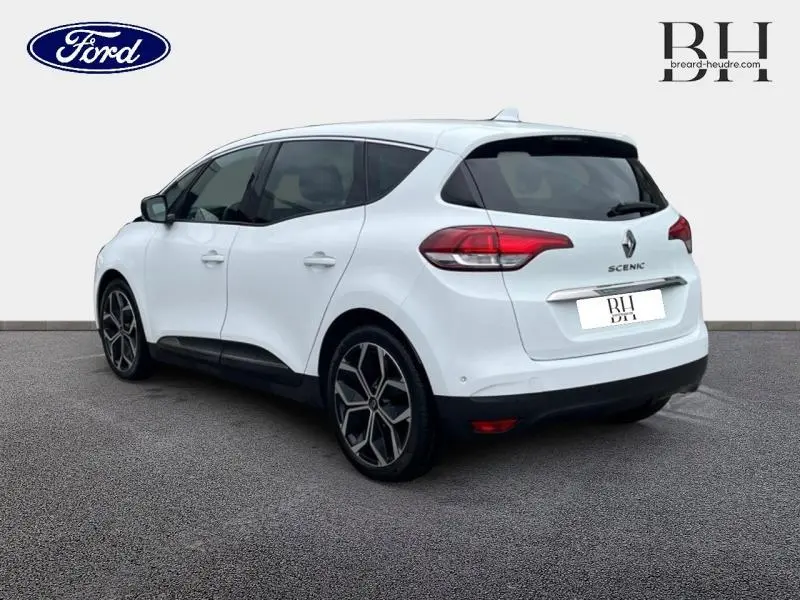 Renault Scénic blanc nacré vue 3/4 arrière droit, avec vitres surteintées et jantes alliage distinctives.