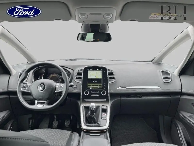 Tableau de bord et volant noir d’un Renault Scénic blanc nacré 2022, vue frontale centrée sur la console tactile.