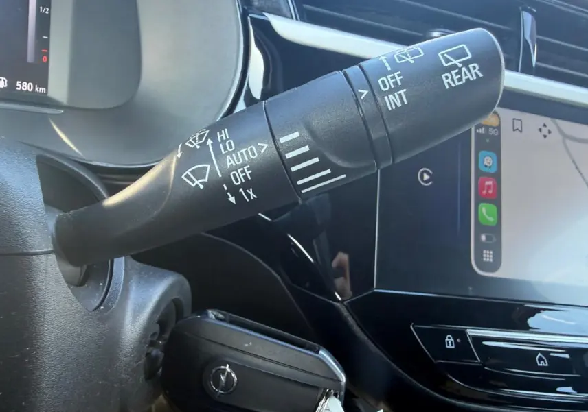 Gros plan sur la commande d’essuie-glace et le tableau de bord numérique d’une Opel Corsa rouge 2025, intérieur noir brillant.