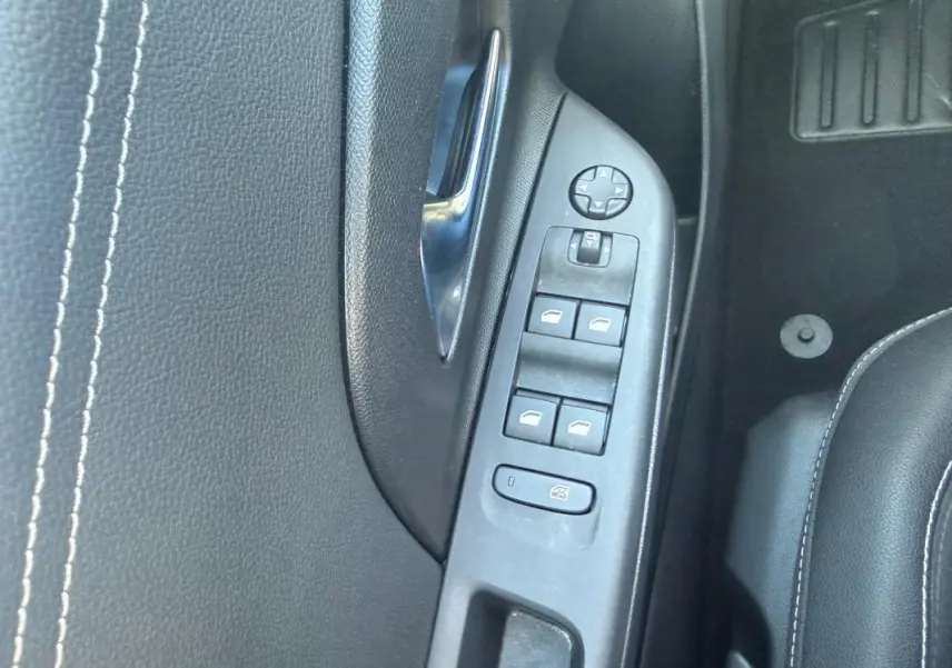 Vue rapprochée de la commande des vitres côté gauche sur porte intérieure noire de l’Opel Corsa rouge 2025.