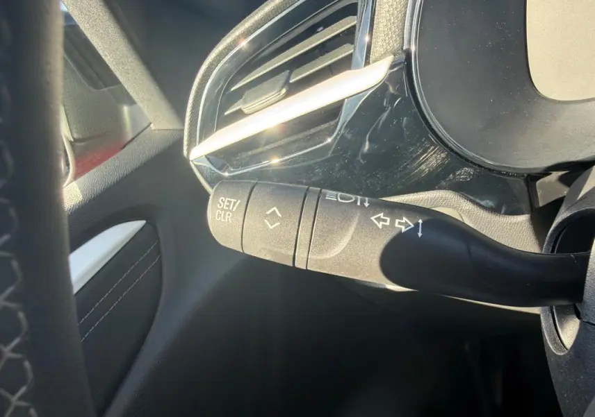 Gros plan sur la manette de clignotant à gauche dans l’habitacle d’une Opel Corsa rouge 2025, version hybride.
