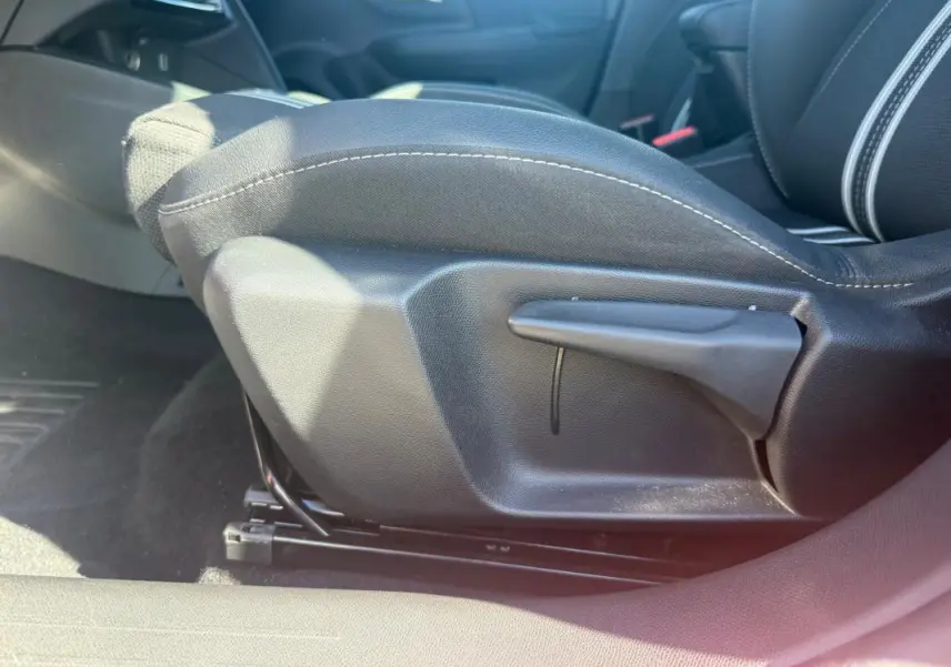 Détail de la commande de réglage manuel du siège avant droit de l’Opel Corsa rouge 2025, version 1.2 Turbo Hybrid.