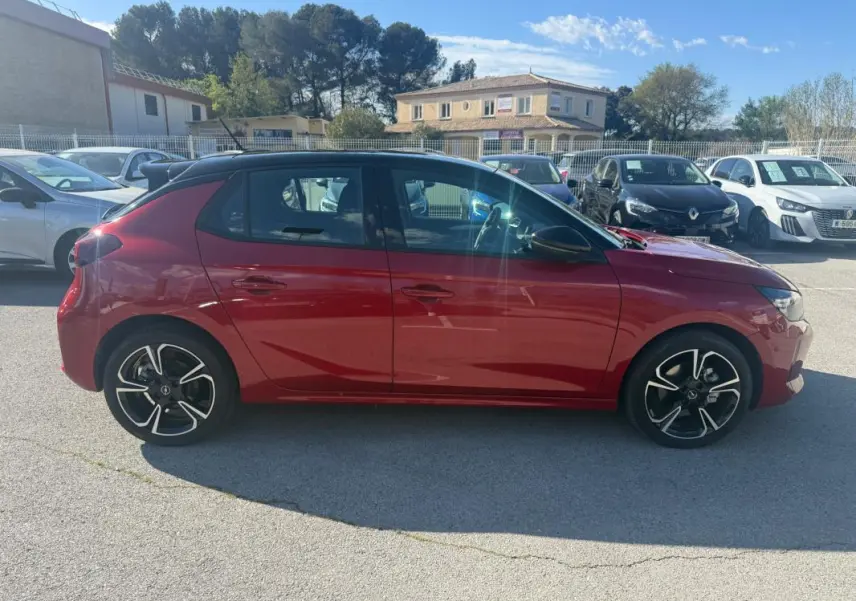 Opel Corsa 2025 rouge vue de profil côté gauche, avec jantes alliage noires et toit noir contrasté.