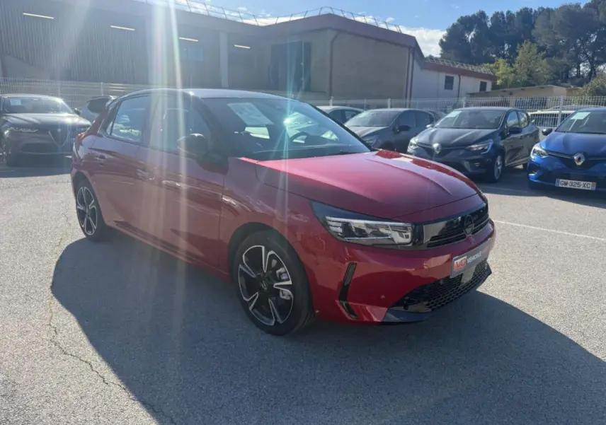 Opel Corsa 2025 rouge vue 3/4 avant droit, avec jantes noires et calandre moderne brillante.
