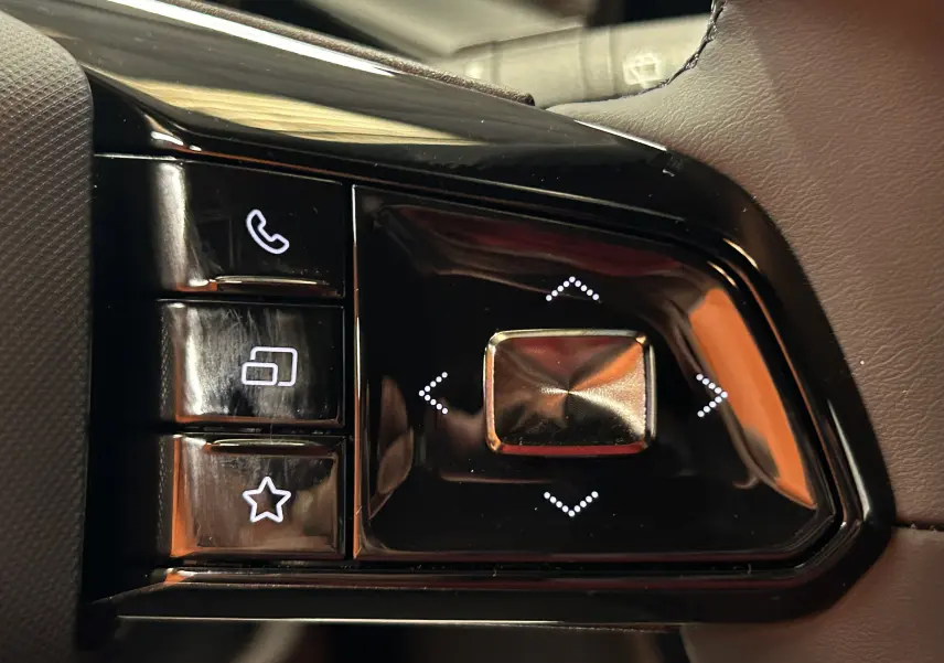 Gros plan sur les commandes noires du volant du MG3 Cosmic Silver, avec boutons tactiles blancs et finition brillante.